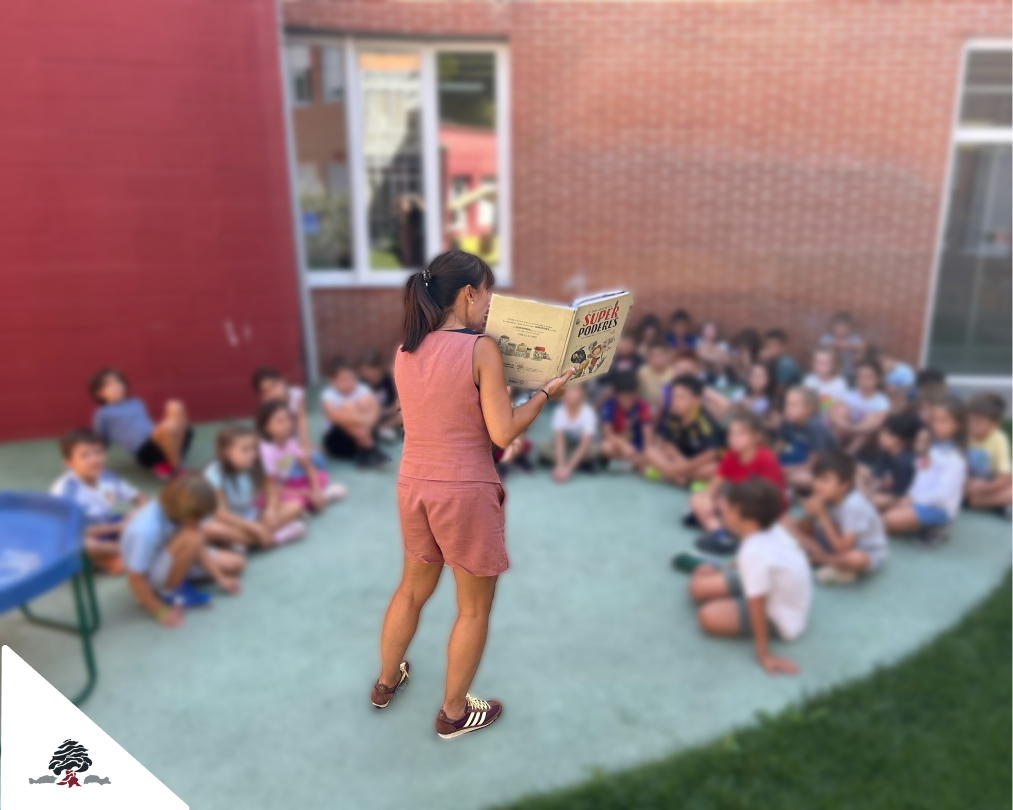 Docente leyendo un cuento sobre la diversidad y los talentos personales a alumnado de Primaria en el patio del Colegio Juan de Lanuza.