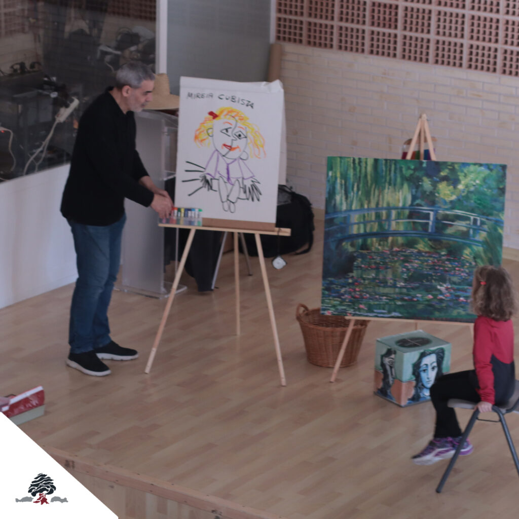 Docente presentando una actividad artística del programa “Menudo Arte” a alumnos de Primaria, junto a reproducciones de obras pictóricas.