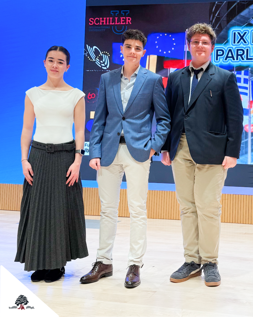 Tres alumnos del Colegio Juan de Lanuza posando en el escenario tras su participación en el Modelo de Parlamento Europeo, en una jornada de debate académico.