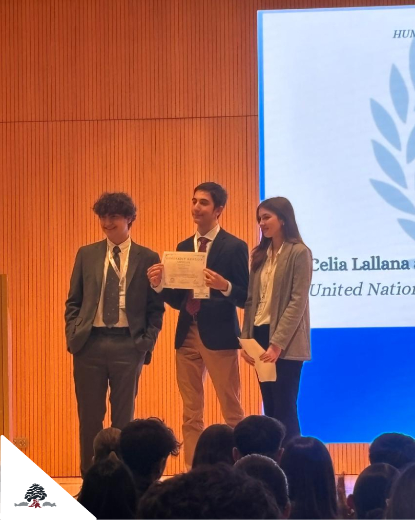Tres alumnos del Colegio Juan de Lanuza en el escenario durante ZARAMUN, uno de ellos sosteniendo un diploma tras recibir una mención honorable en el Modelo de Naciones Unidas.