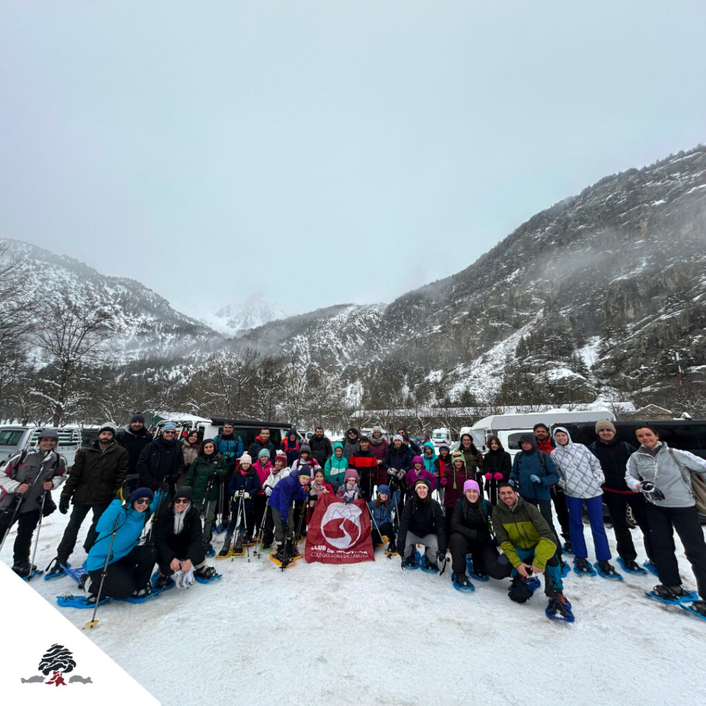 Grupo de alumnos, familias y profesores del Club de Montaña Juan de Lanuza durante la salida con raquetas de nieve en Baños de Panticosa, con paisaje nevado de montaña al fondo.